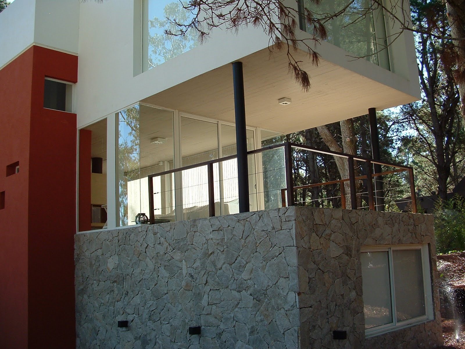 Fachada moderna com pedra empilhada e amplas janelas — projeto villa del puente, por GJF estudio, em Costa del Este