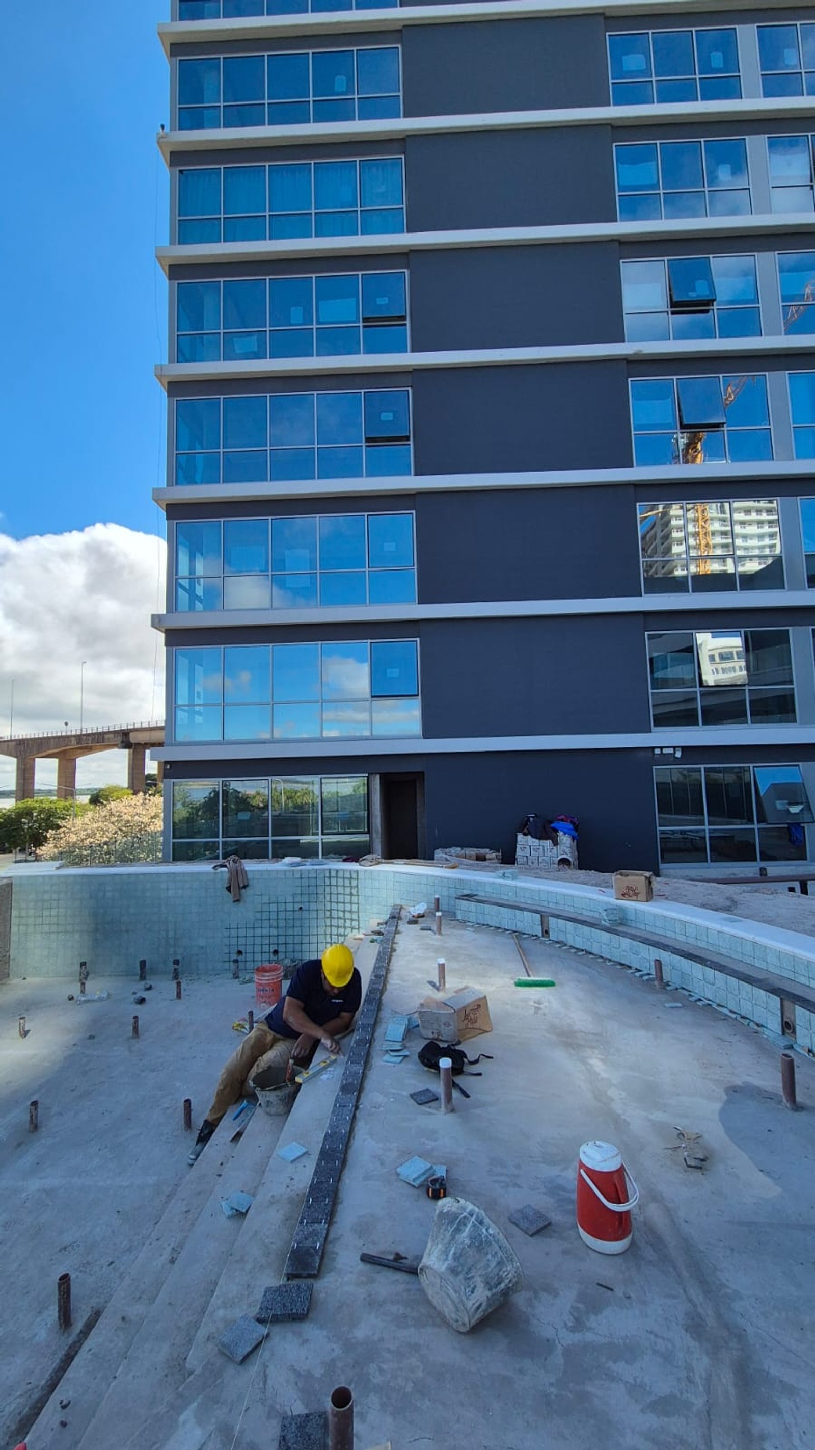 construcción de piscina frente a edificio moderno — proyecto Obra Piscina Los Boulevares Corrientes en Proceso, por Aquamare Piscinas, en Corrientes