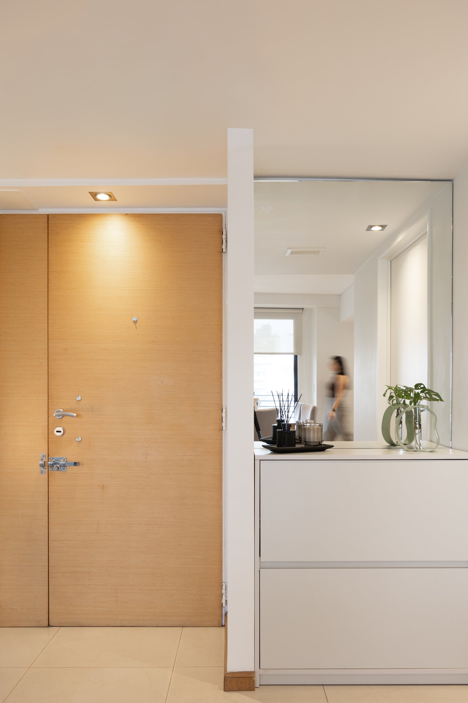 Puerta de madera y espejo con mueble blanco en recibidor moderno — proyecto Rio, por Martina Kleinert, en Saavedra