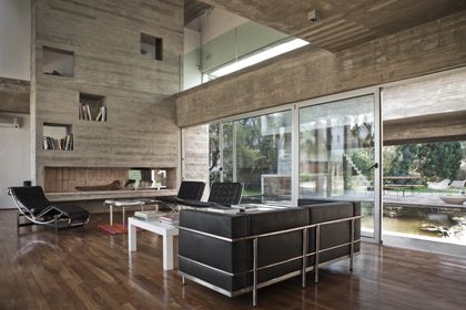 Living moderno con doble altura, hormigón y amplios ventanales al lago — proyecto Casa Torcuato, por Luciano Kruk