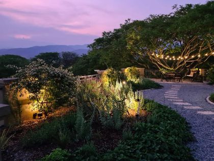 Jardín nocturno iluminado con pérgola de madera y plantas trepadoras — proyecto Los pasos de Justina. Club de Campo El TIPAL, por Marina Caballer