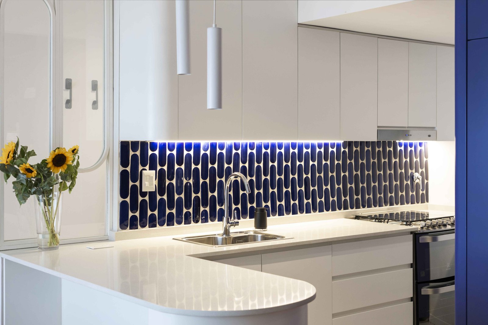 Cocina moderna con backsplash azul y muebles blancos — proyecto Julián Alvarez, por Bouré Studio, en Palermo