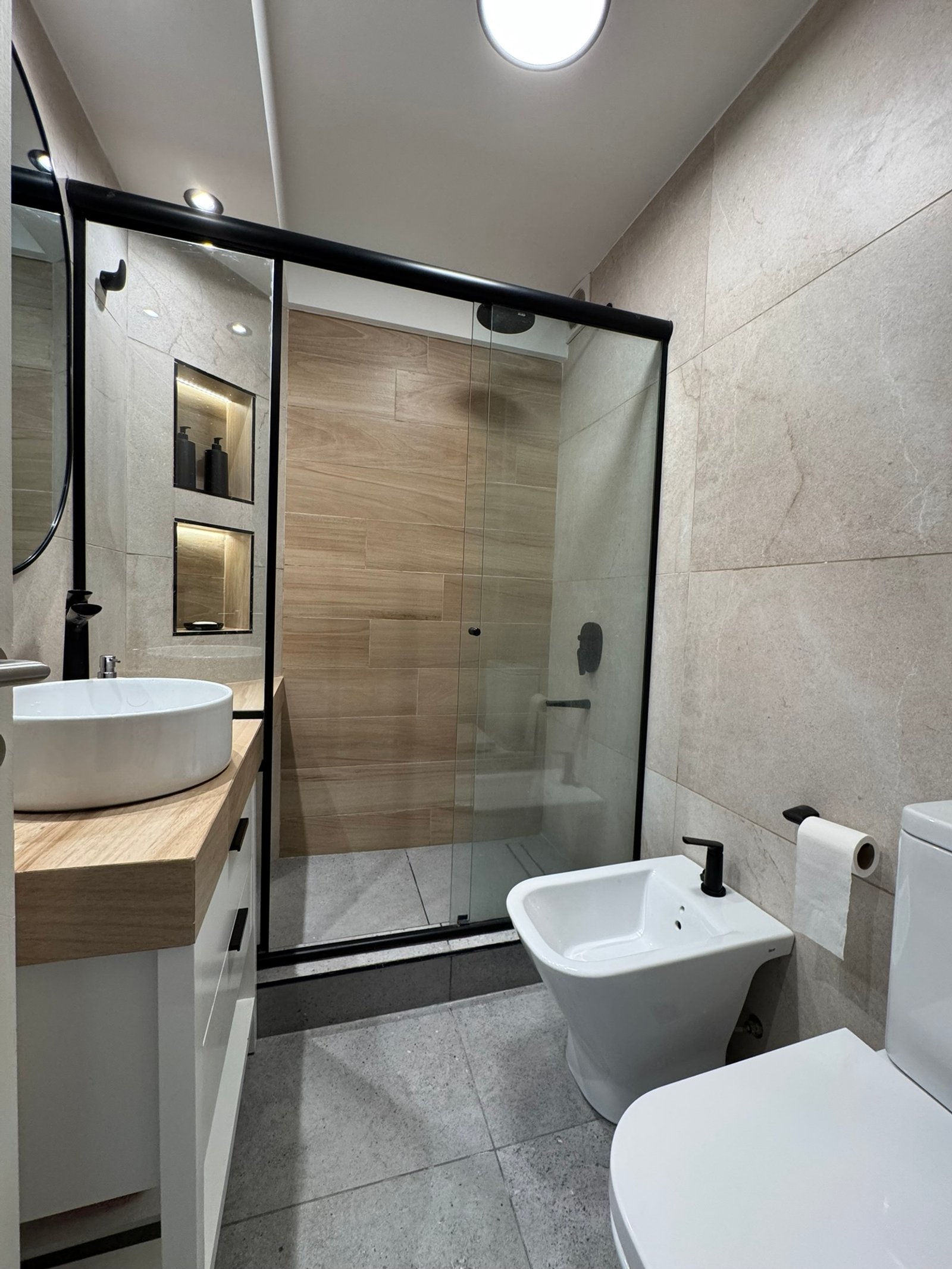 Baño moderno con ducha, bidet, inodoro y lavabo sobre mueble de madera — proyecto Vera II, por MDBK Arquitectura, en Villa Crespo