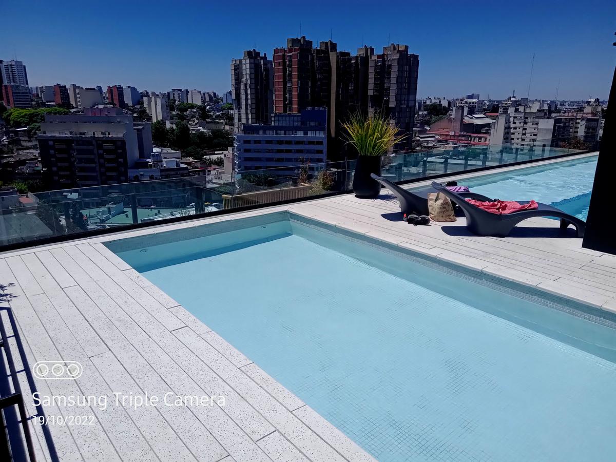 Piscina na cobertura com deck branco e vista da cidade — projeto Obra Urquiza 1640, por Soluciones Bralum, em Buenos Aires
