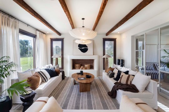 Living moderno con vigas de madera y sofá curvo — proyecto El Descanso, por MUCHTEK, en Provincia de Buenos Aires
