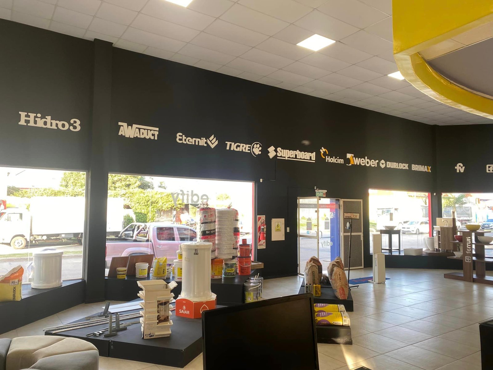 Local comercial moderno con pared negra y logos blancos — proyecto Edify Corrientes, Casa de Materiales de Construccion., por Arquitecto Gustavo Maidana, en Corrientes