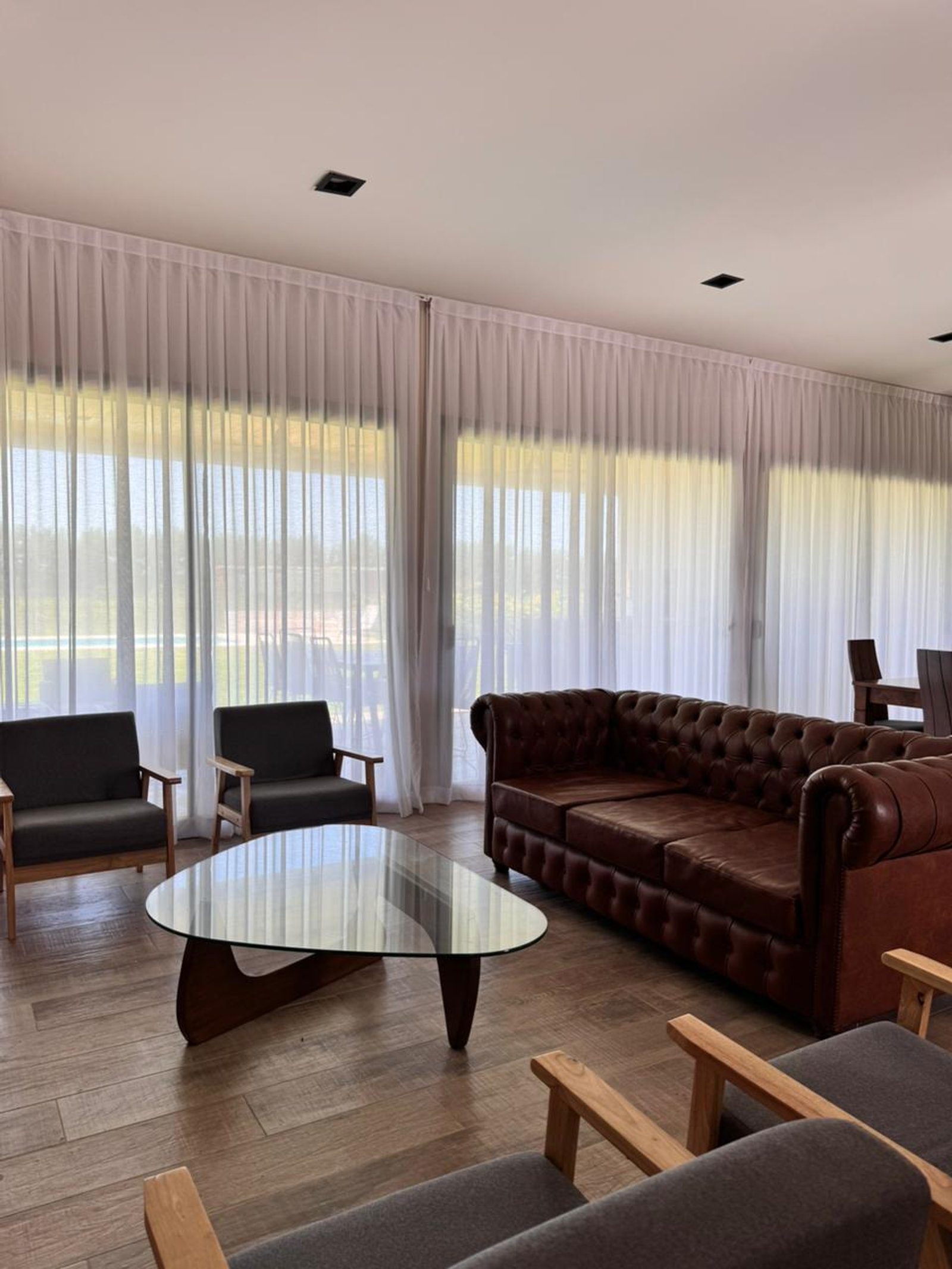 Sala de estar com sofá de couro e grandes janelas — projeto Proyecto residencial en Bella Vista | Línea A30, por AROPACK, em Bella Vista