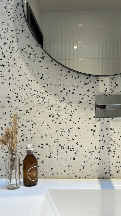 Baño contemporáneo con espejo circular y mesada blanca de terrazo — proyecto Casa 55, por RY Construir Estudio, en San Vicente