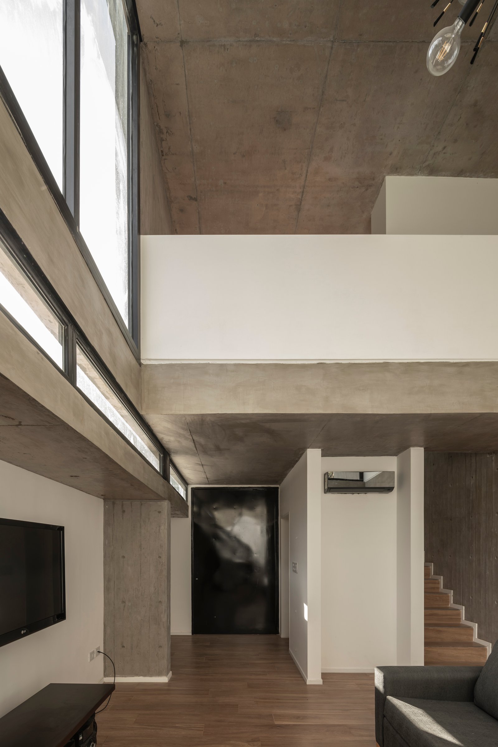 Sala de estar moderna com concreto aparente e janelas grandes — projeto Casa Emilia, por Grupo CRBN, em Parque Leloir