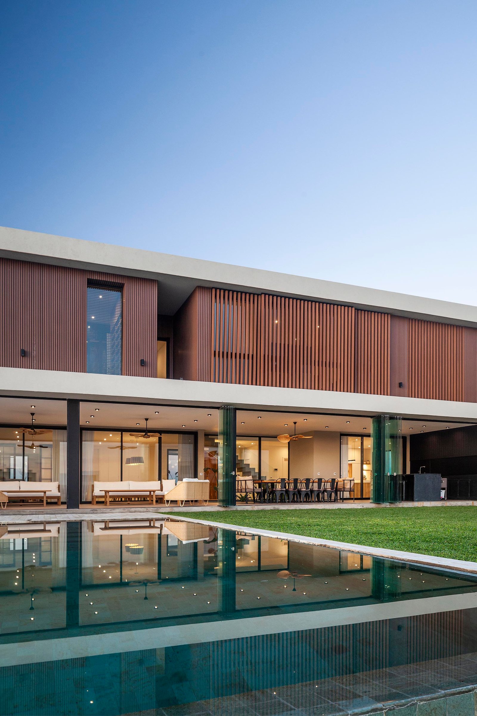 Fachada moderna con revestimiento de madera y piscina integrada — proyecto CASA C313, por A'PRIMA - Arquitectura Sustentable, en Provincia de Buenos Aires