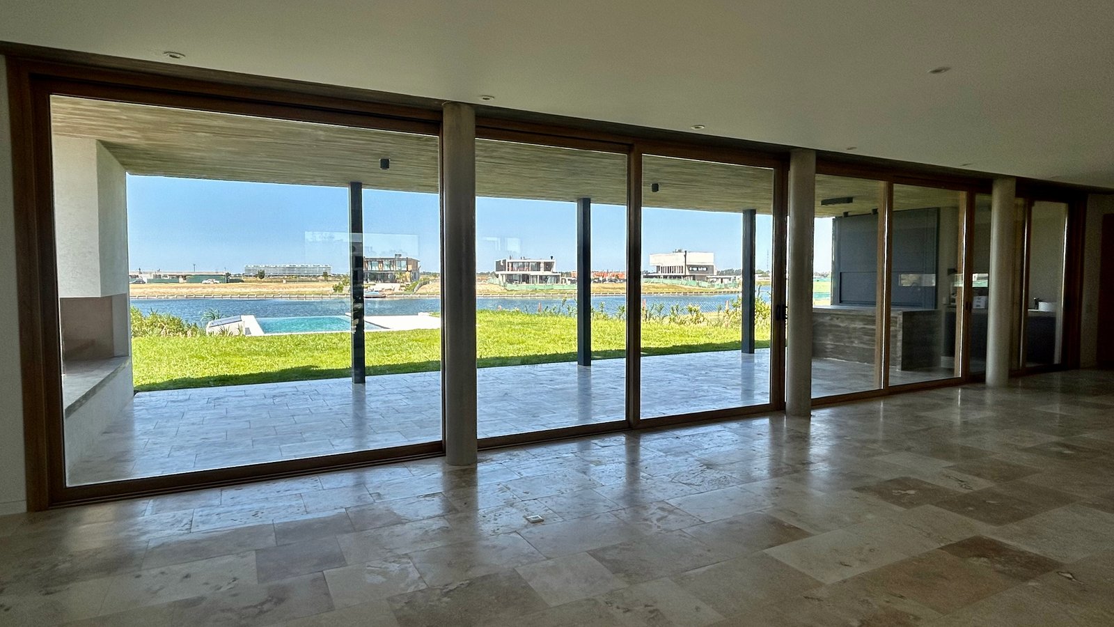 Living moderno con vista al agua y ventanales de piso a techo — proyecto Casa Puentes, por Guerrero Arquitectos, en Rincón de Milberg
