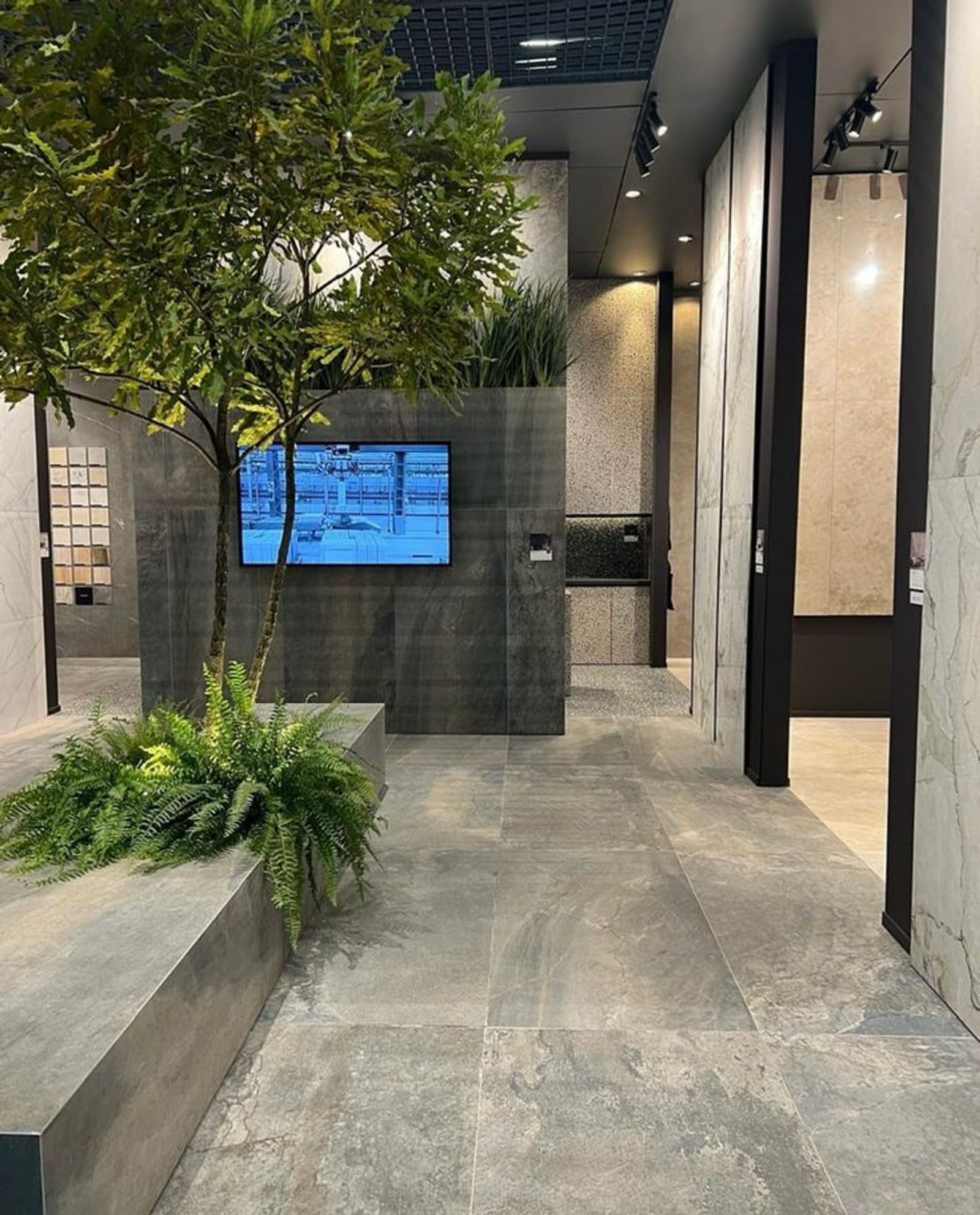 Hall de exhibición moderno con revestimientos de piedra y vegetación — proyecto Expo Revestir 2025, por Vite Porcellanato, en São Paulo