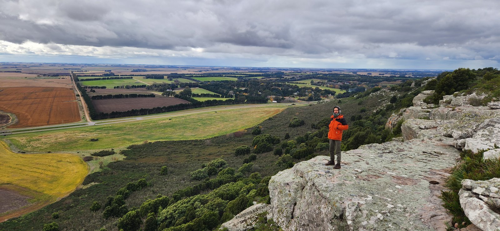 Pessoa em afloramento rochoso sobre paisagem rural vasta — projeto Reserva Naural Paititi, por Estudio Rifahi, em Sierra de los Padres
