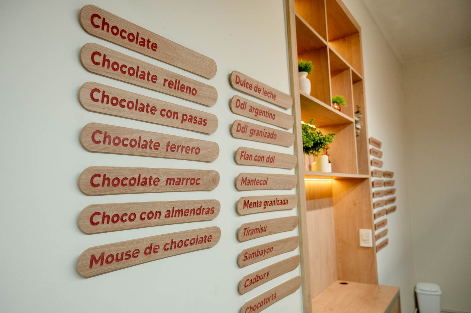 Loja de chocolates com placas de madeira e prateleiras — projeto Flodies Cremas heladas, por Ailén Lucero Arquitectura, em La Plata
