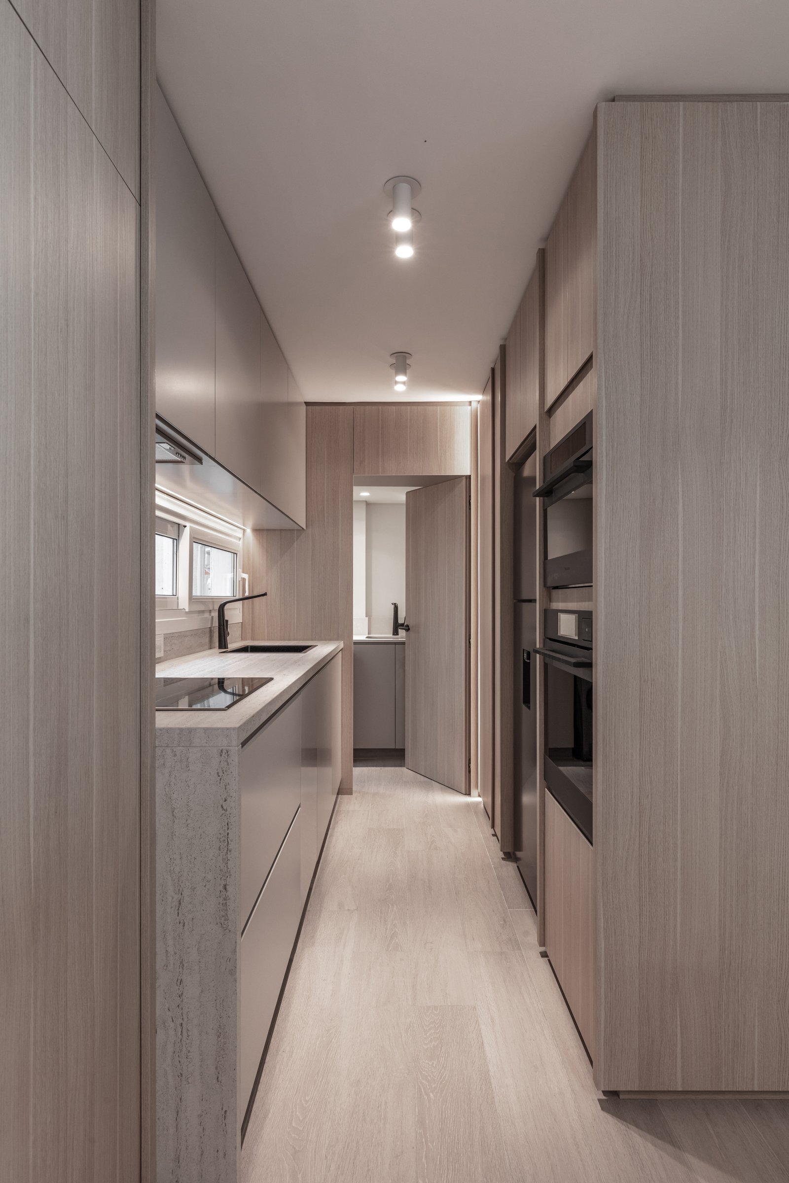 Cozinha estreita moderna com painéis e móveis de madeira clara — projeto Eslovenia | Pied-à-terre | Lucia Quinteros, por Ren Studio, em Cdad. Autónoma de Buenos Aires