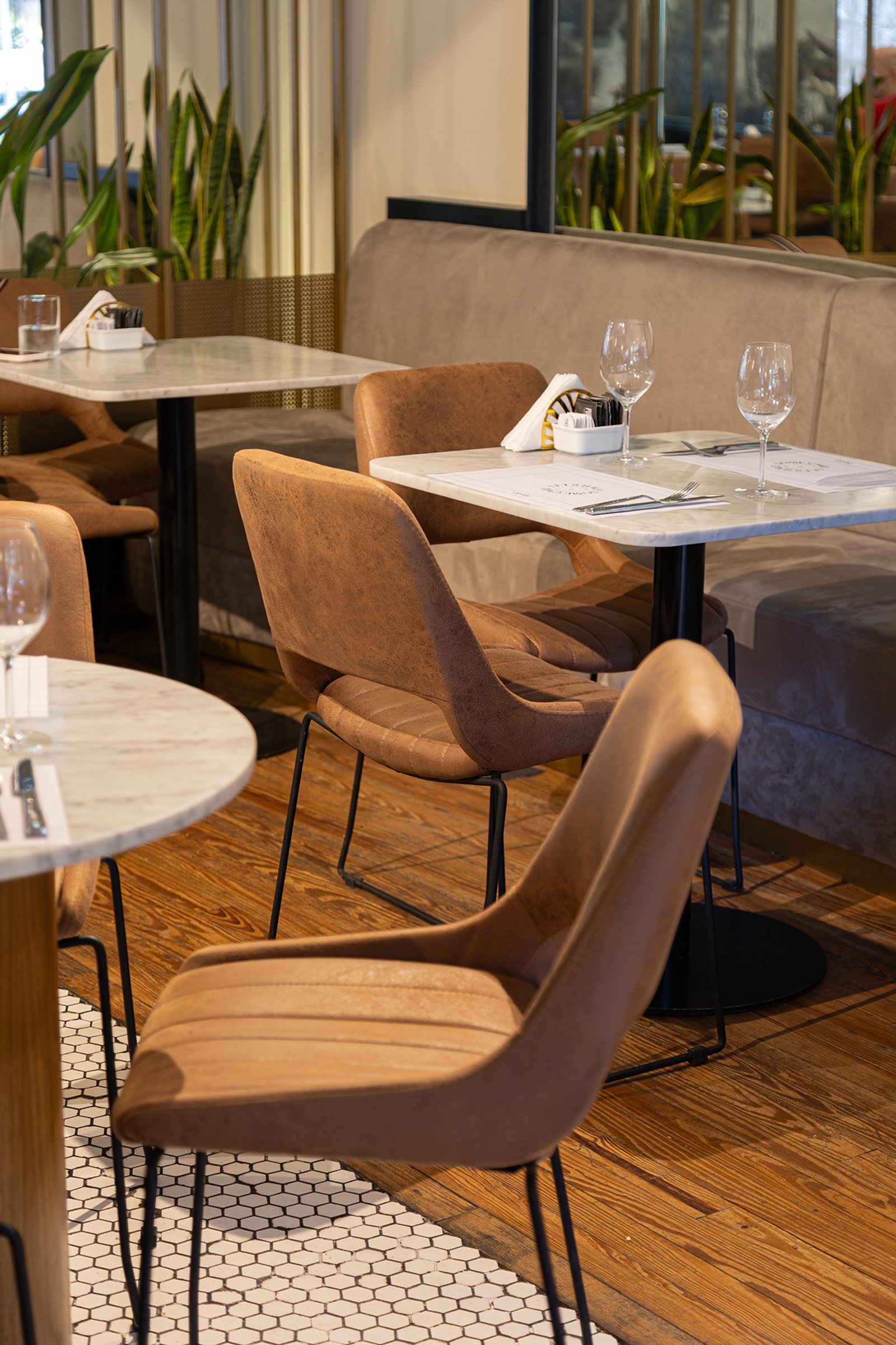 Comedor moderno con mesas de mármol, sillas y plantas interiores — proyecto Olivier BA, por Gaby Alfonso, en Belgrano