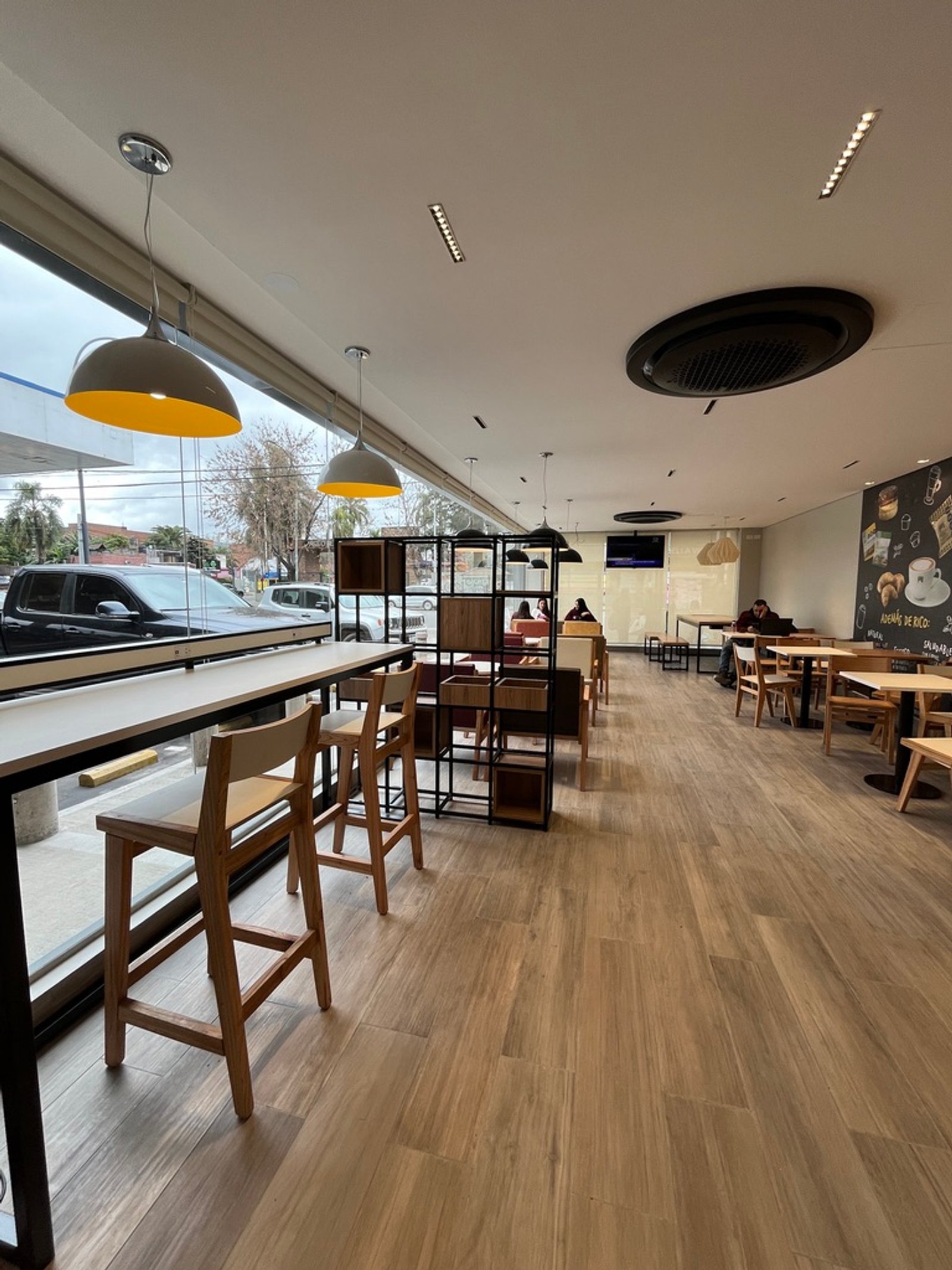 Interior de cafetería moderna con mucha luz natural y barras de madera — proyecto Full YPF Muniz, por Arcucci Arquitectura, en Muñiz
