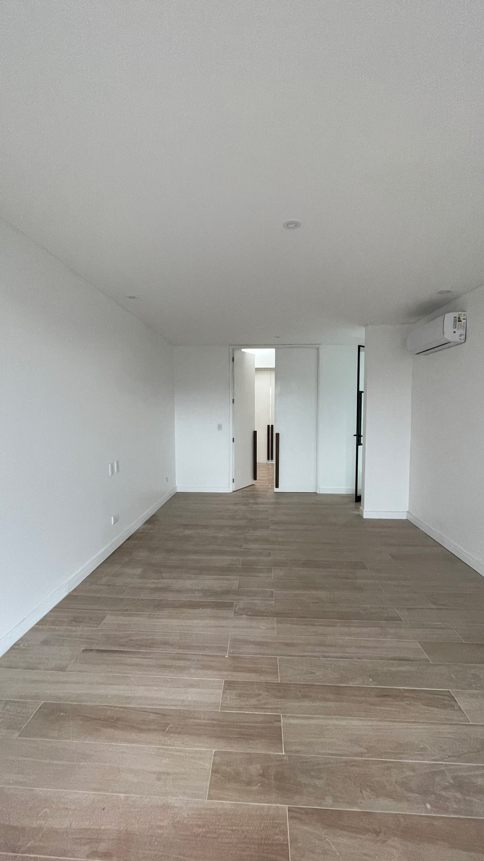 Pasillo y sala moderna vacía con piso de madera clara — proyecto Casa ER , por Hermann Arquitectos, en Arribeños 1611