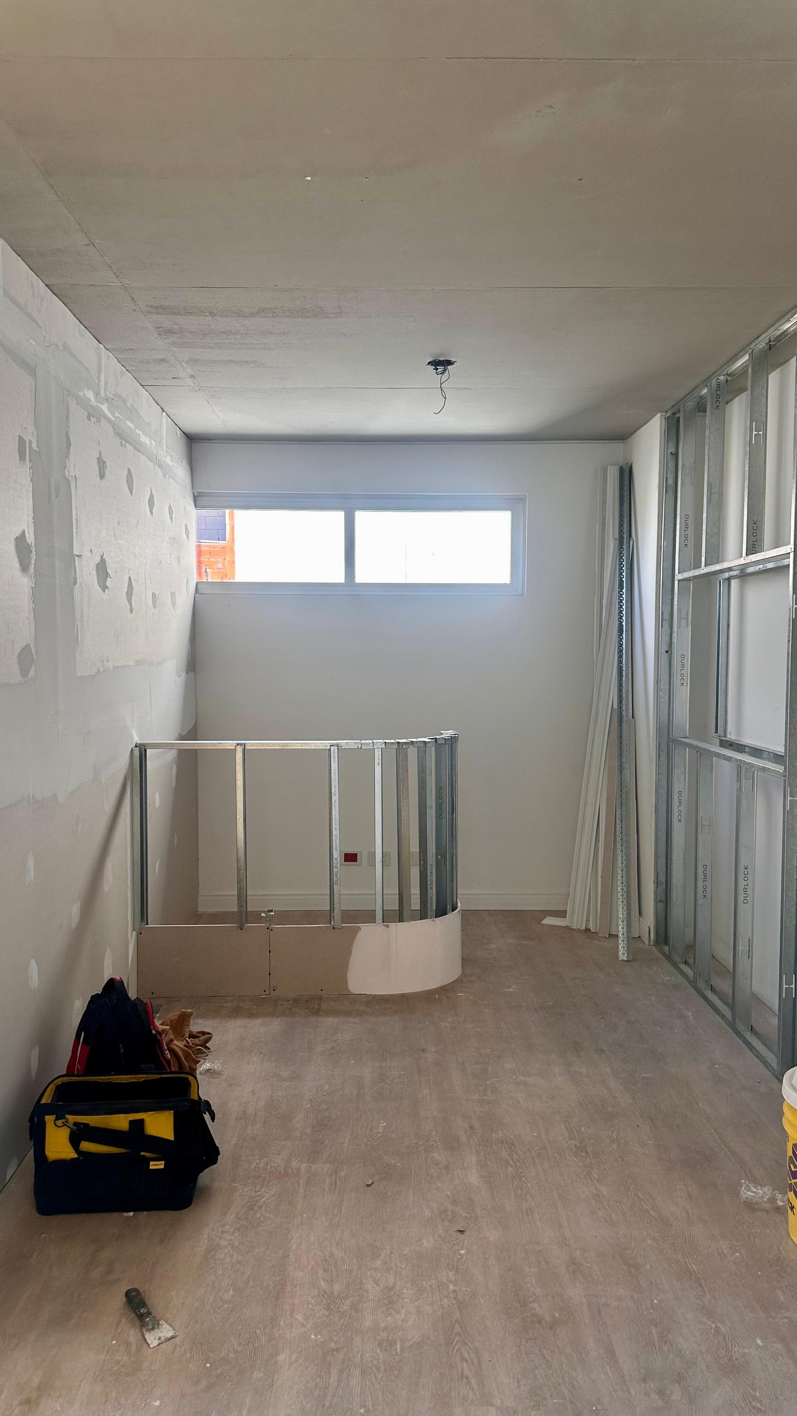Espacio interior en construcción con pared curva y bolsa de herramientas — proyecto G L A M A L I N E, por Arq. Emiliano Ciaburri, en Buenos Aires