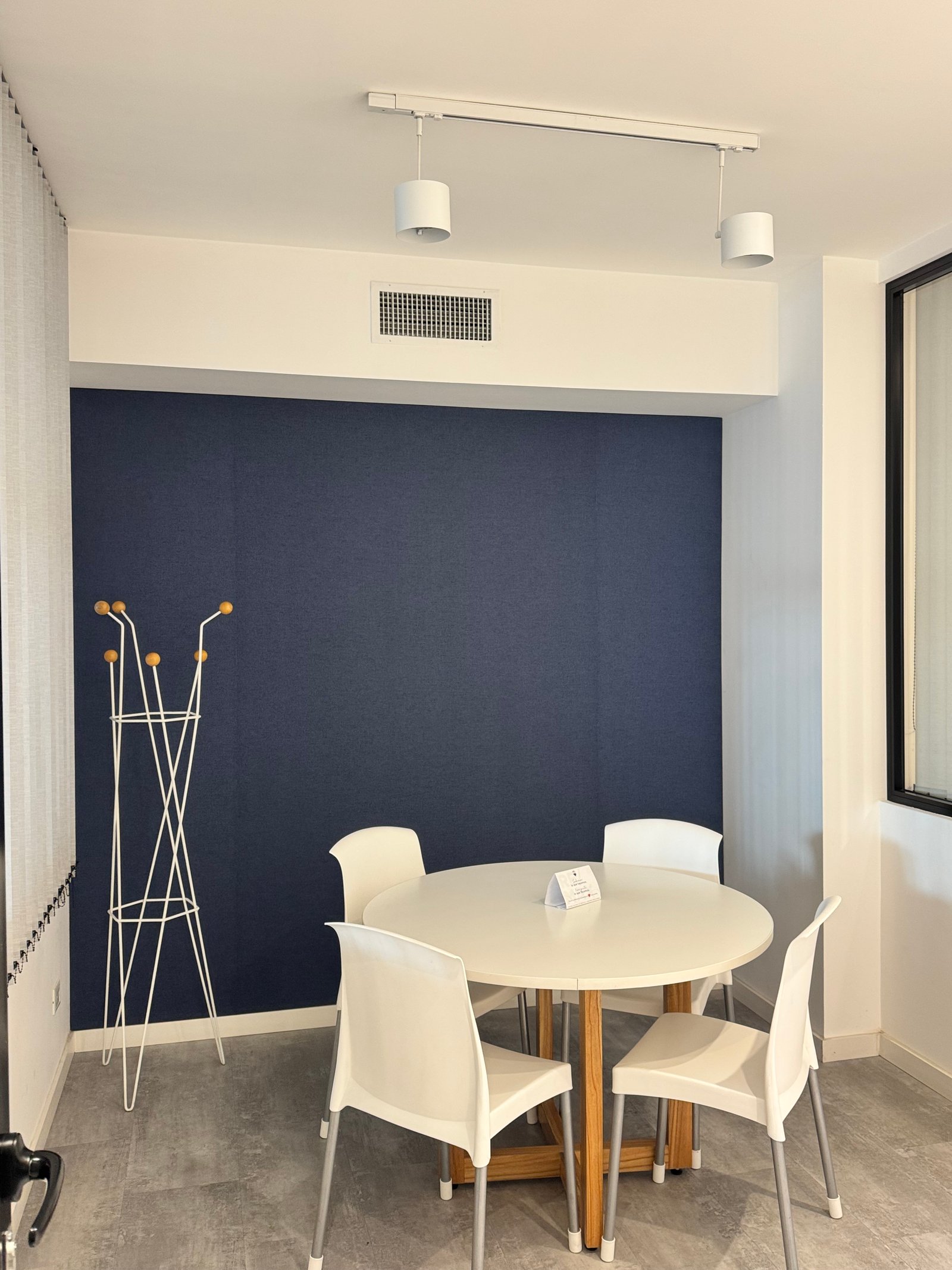 Comedor de oficina moderno con pared azul oscuro y mesa redonda blanca — proyecto REMAX DEL PLATA , por Estudio Grupo 32, en Buenos Aires