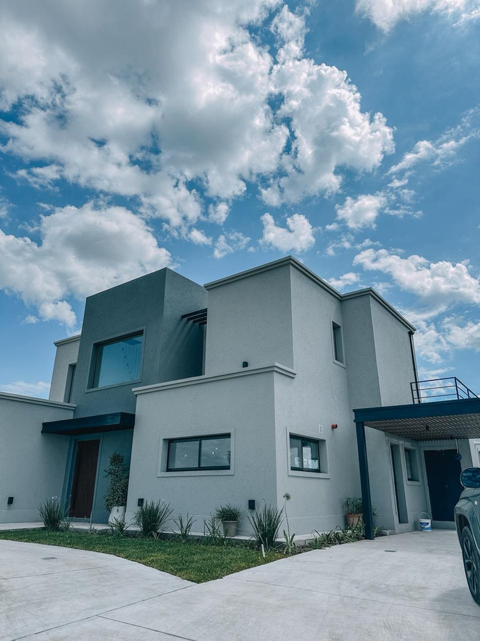 Fachada moderna gris con grandes ventanas y cielo nublado — proyecto Proyecto realizado con sistema A30 – Village Plaza, Bella Vista, por AROPACK, en Bella Vista