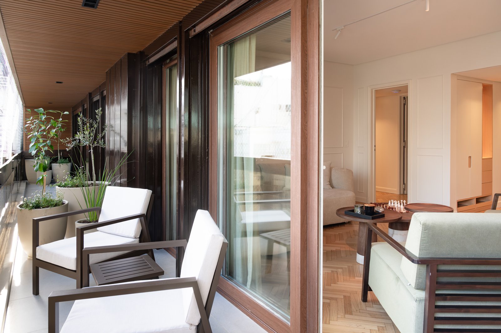 Varanda moderna com sofá branco, madeira escura e plantas — projeto ALVEAR TYM, por AB ARQUITECTURA, em Recoleta