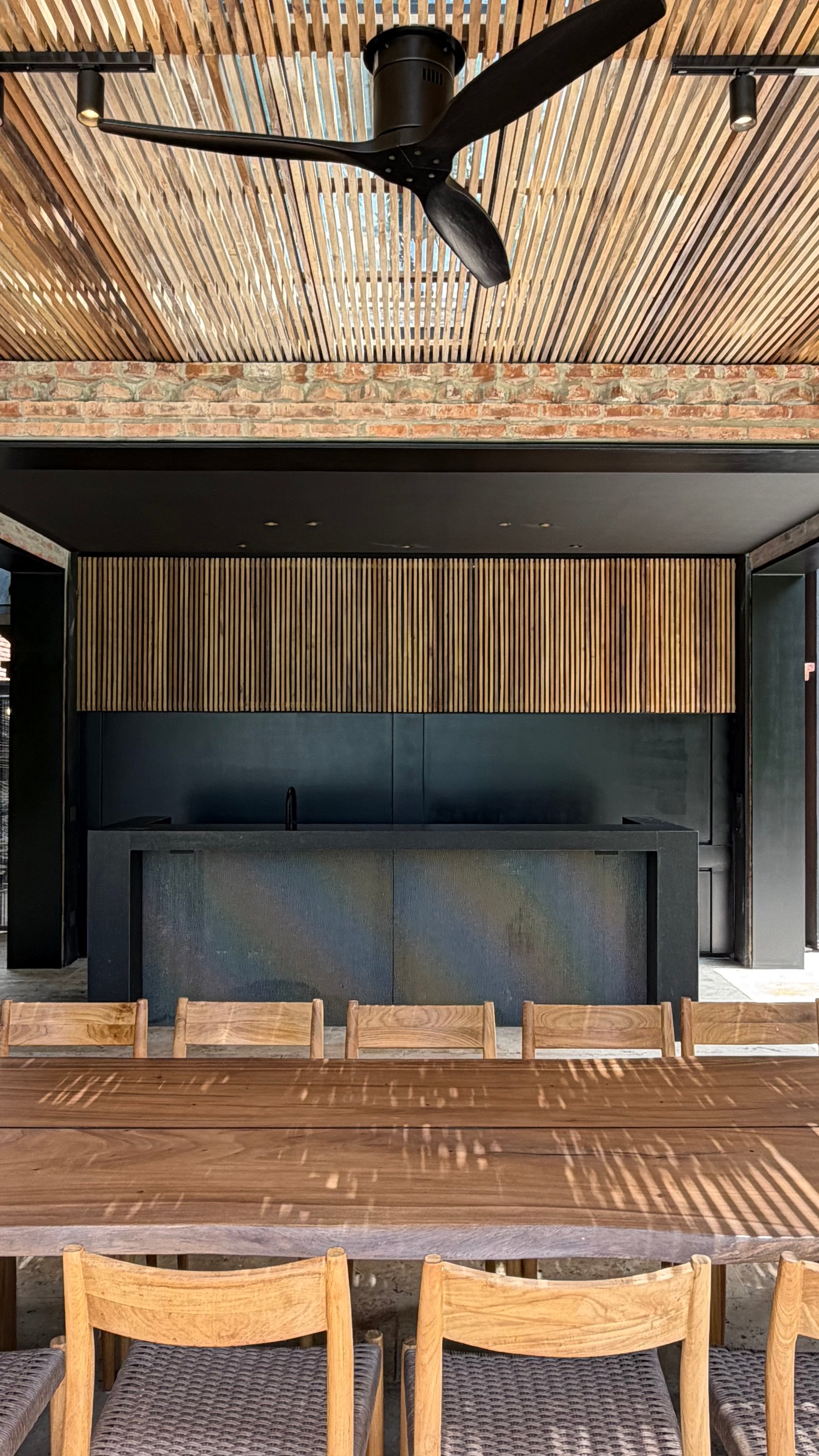 Sala de jantar e cozinha externa com teto de madeira, ventilador preto e mesa grande — projeto Casa JCP, por radovic_arquitecto, em José C. Paz 850