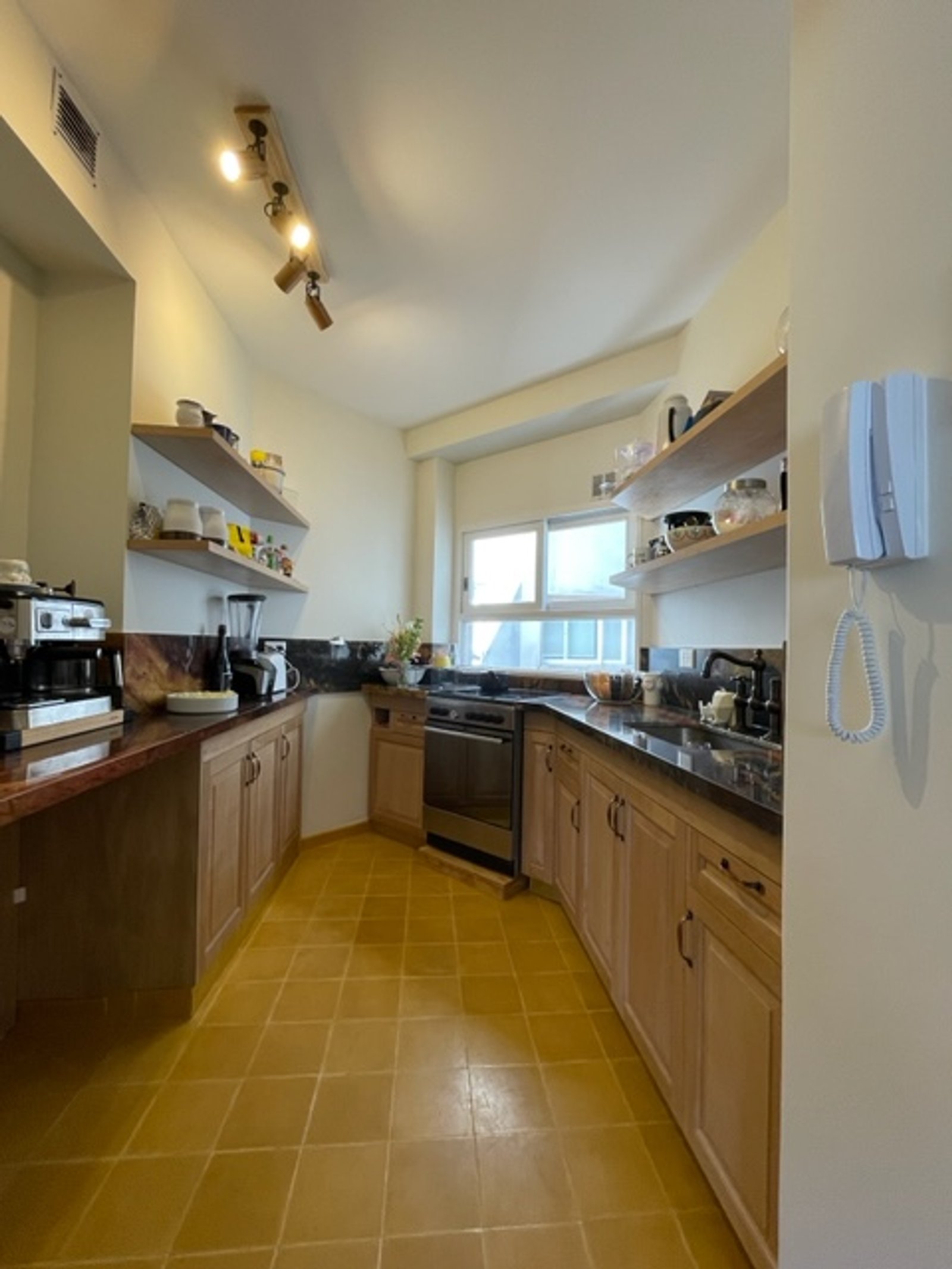 Cocina con piso de cerámica terracota, muebles de madera natural y mesada de piedra negra — proyecto Chenaut , por Estudio NET Arquitectura , en Av. Gral. Indalecio Chenaut 1739