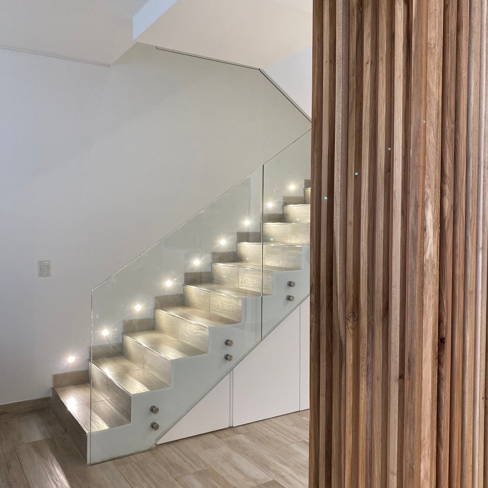 escalera moderna flotante con barandas de vidrio e iluminación indirecta — proyecto Nicolas Repetto, por MDBK Arquitectura, en Caballito
