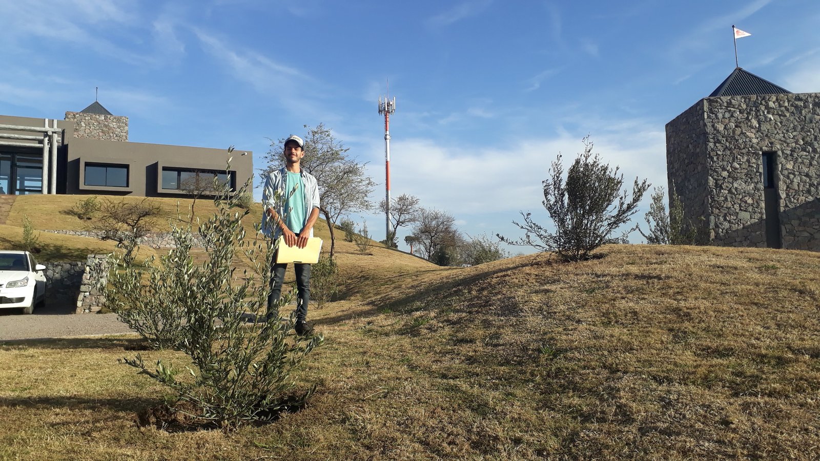 Casa moderna en ladera con torre de piedra y persona — proyecto El Terrón, por Estudio Rifahi, en Mendiolaza