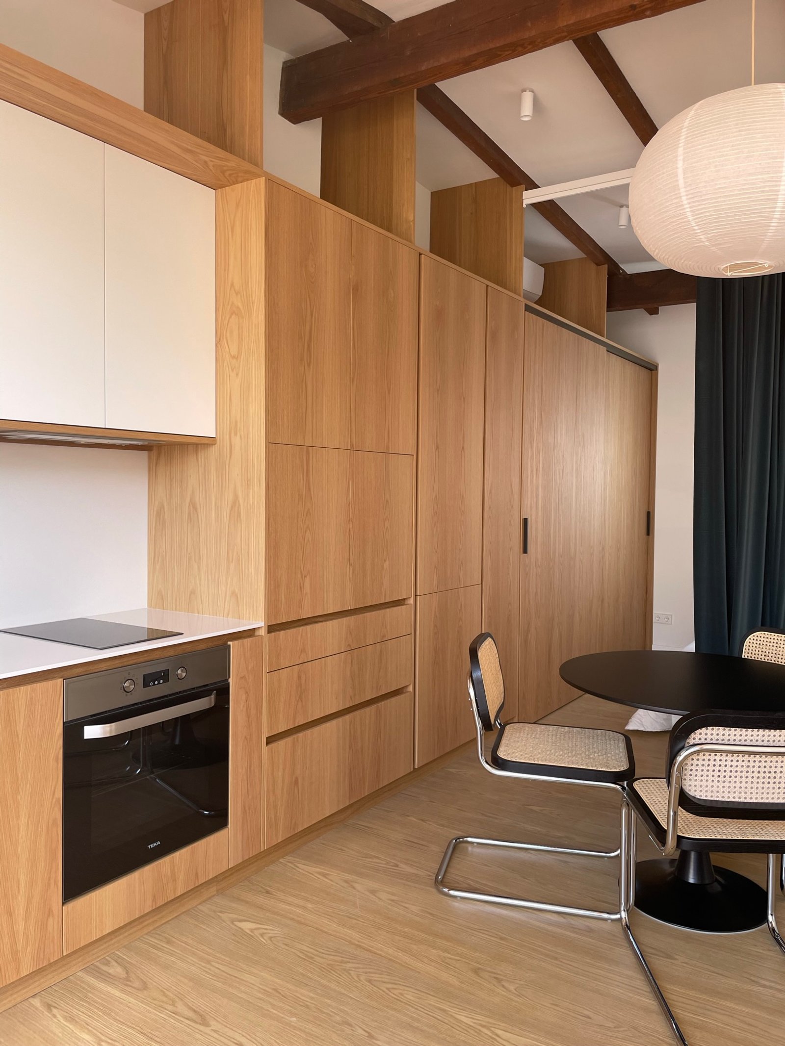 Cozinha moderna com vigas aparentes, madeira natural e sala de jantar integrada — projeto Burriana, por JT ARQUITECTURA, em Valencia