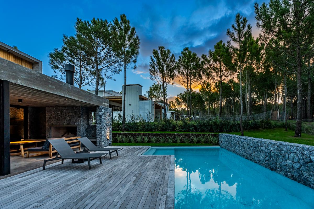 Piscina moderna com deck de madeira e cenário de floresta — projeto casa la huella, por Guerrero Arquitectos, em Pinamar