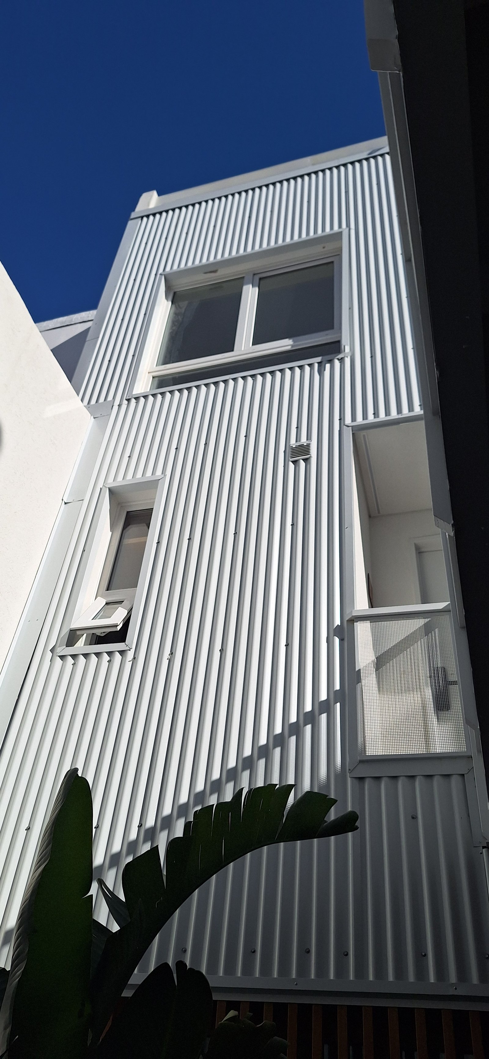 fachada moderna con revestimiento de metal corrugado y vegetación — proyecto Edificio Escribano, por LW Lopez Wolder arquitectos, en Pasaje Escribano 66