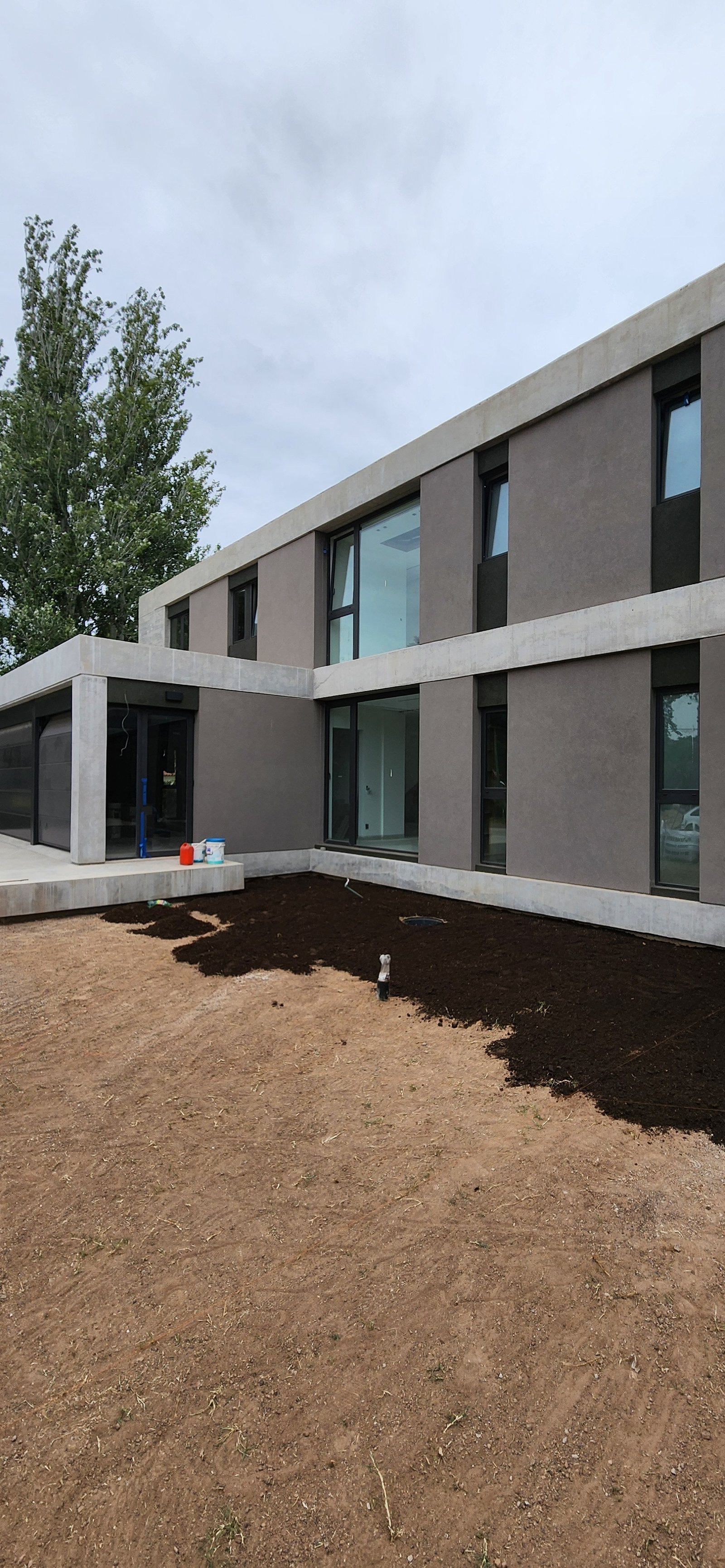Fachada moderna con volúmenes de hormigón y grandes ventanales — proyecto Casa CAD, por Estudio Rifahi, en Moreno
