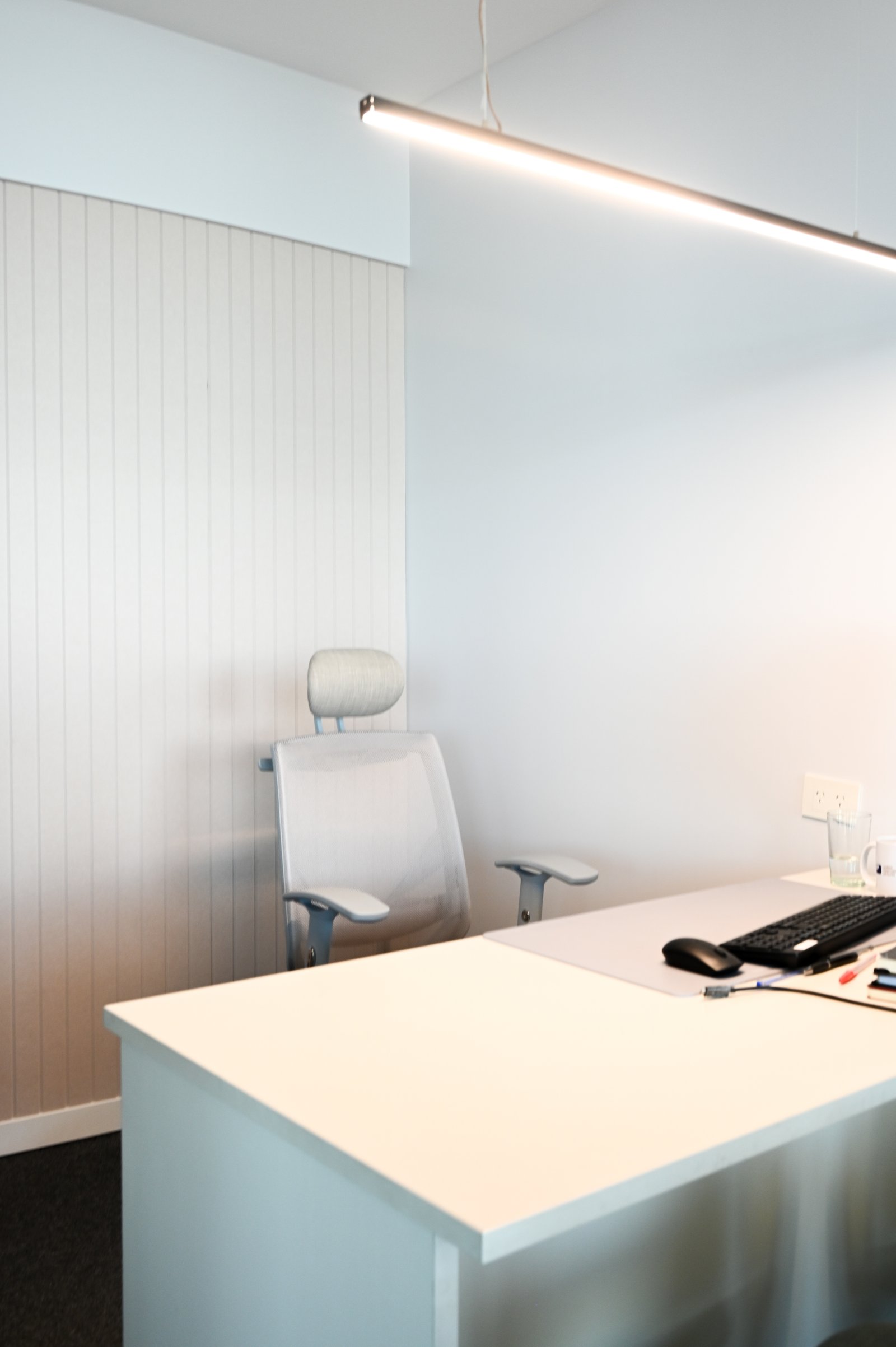 Escritório moderno com mesa branca, cadeira ergonômica e parede de madeira — projeto Oficinas UIP, por cromo., em Retiro