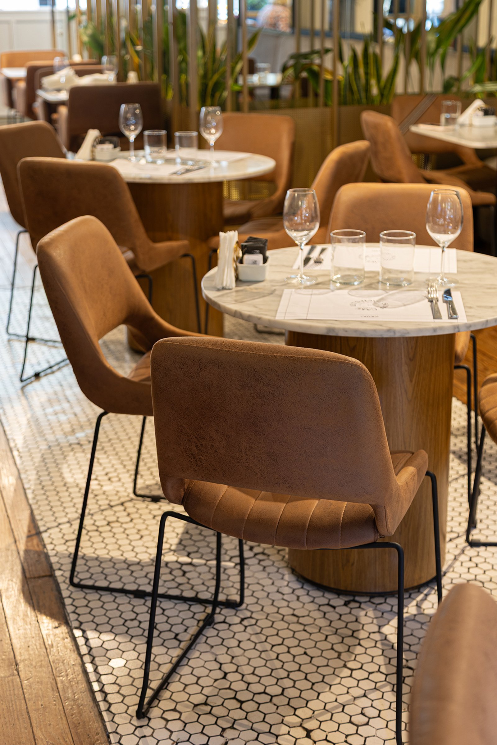 Cadeiras de couro marrons e mesas redondas em sala de jantar moderna — projeto Olivier BA, por Gaby Alfonso, em Belgrano