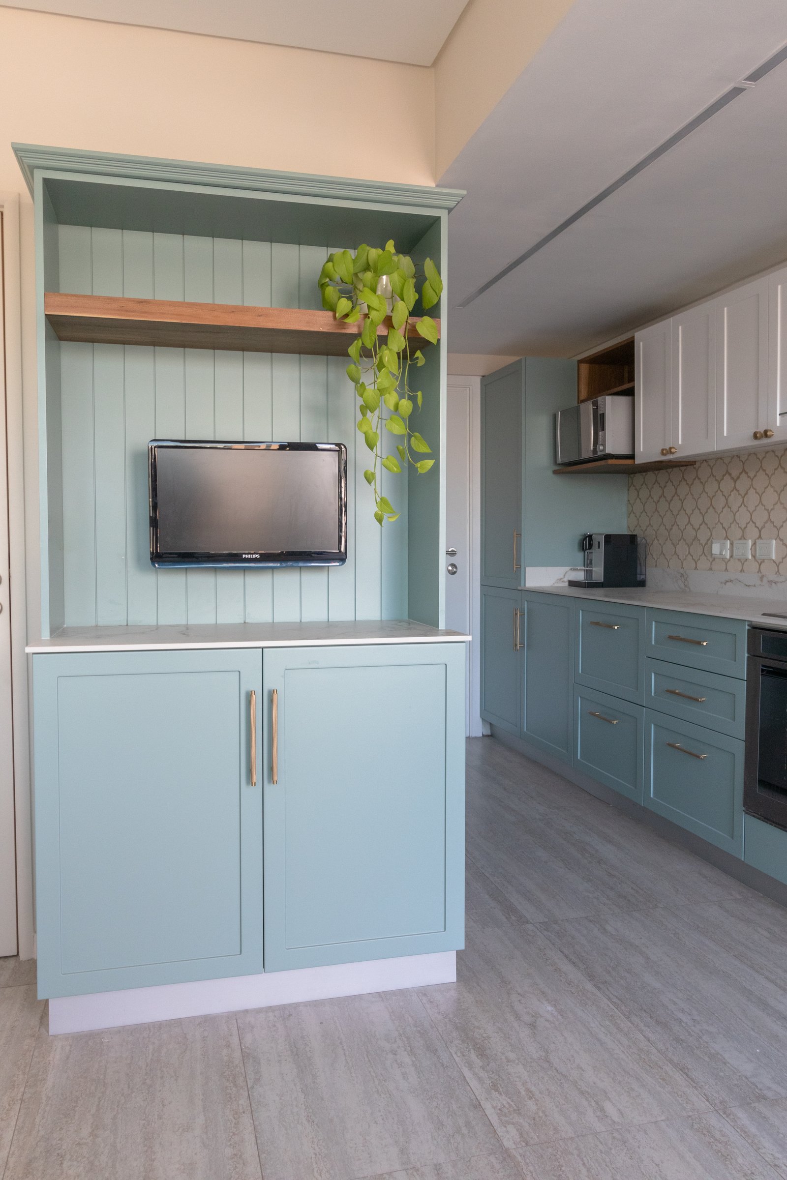 Cocina y living integrado con muebles celestes y pared revestida — proyecto Martinez - Estudio Libria, por ABEJA CONCEPT, en Belgrano