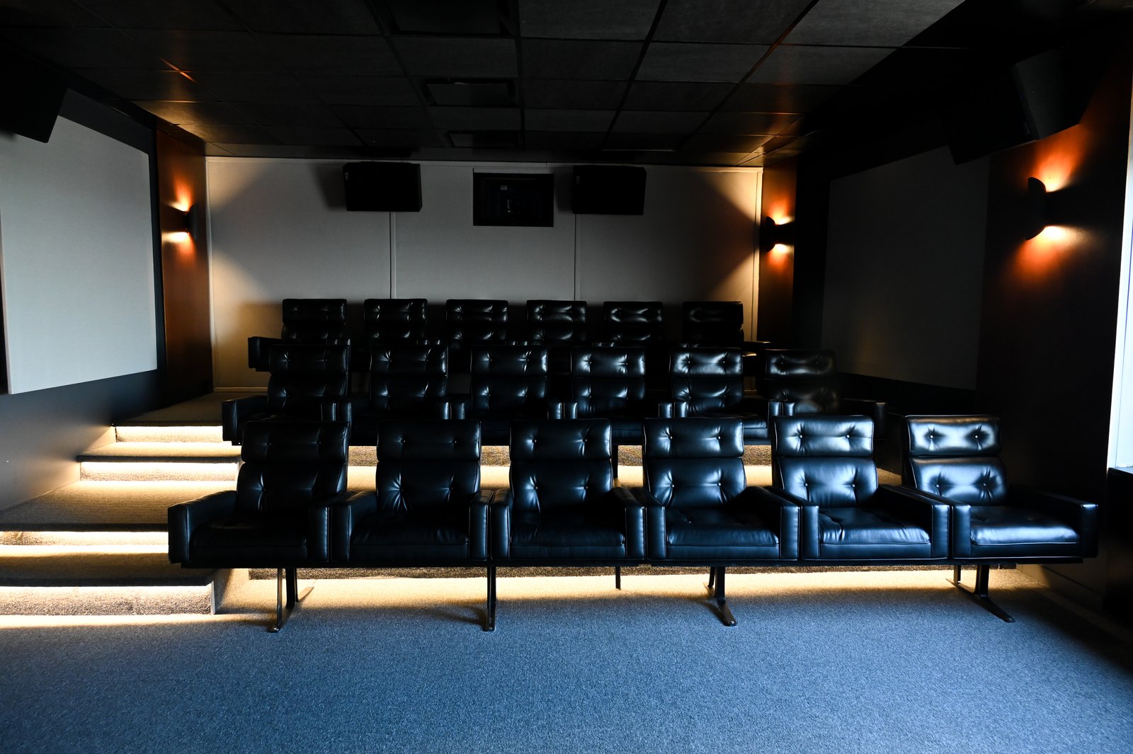 Sala de cinema moderna com assentos de couro preto — projeto Oficinas UIP, por cromo., em Retiro