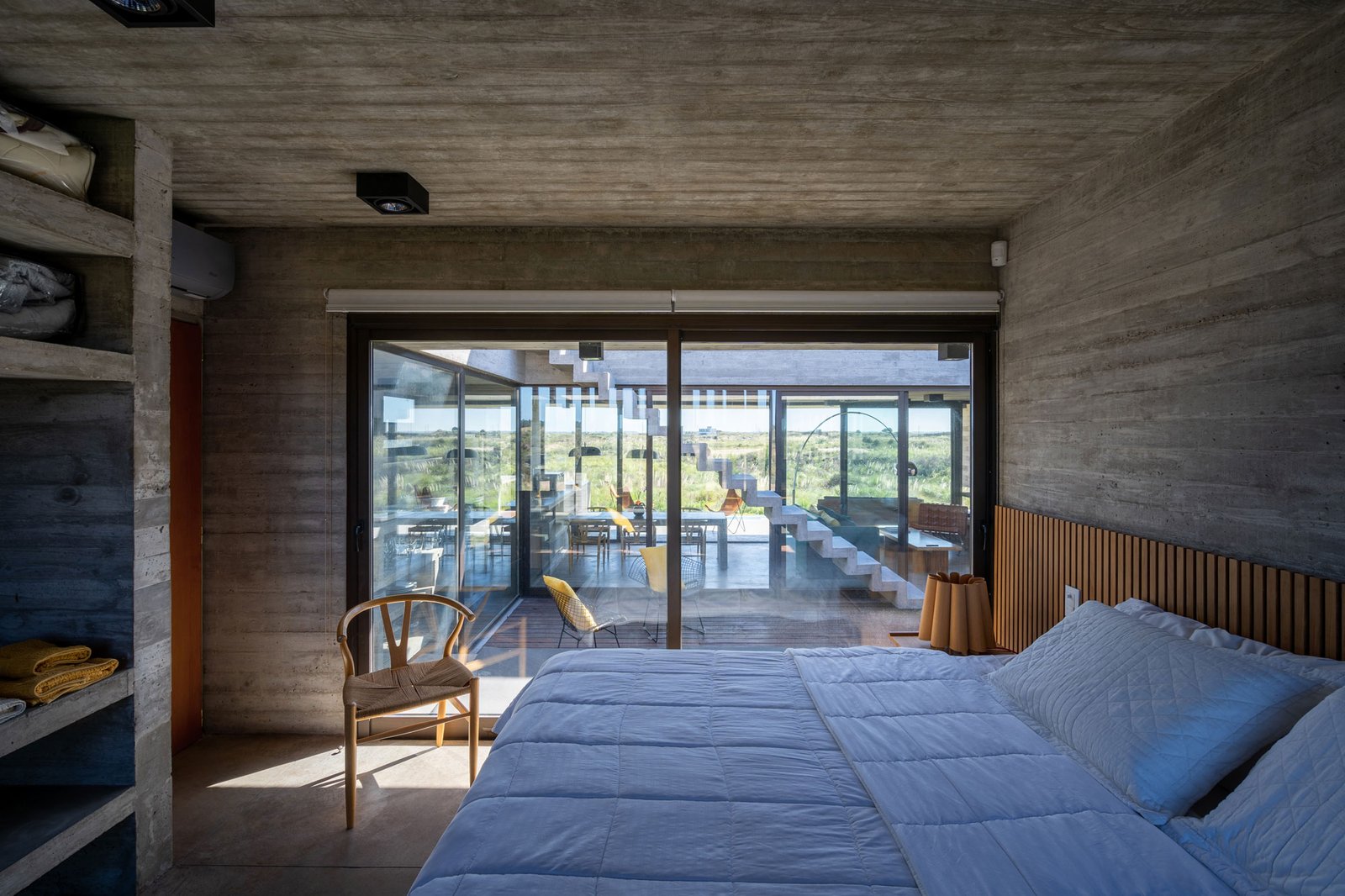 Quarto moderno com concreto aparente e vista externa — projeto Casa Médanos, por Besonías Almeida arquitectos, em JWRC+MQ
