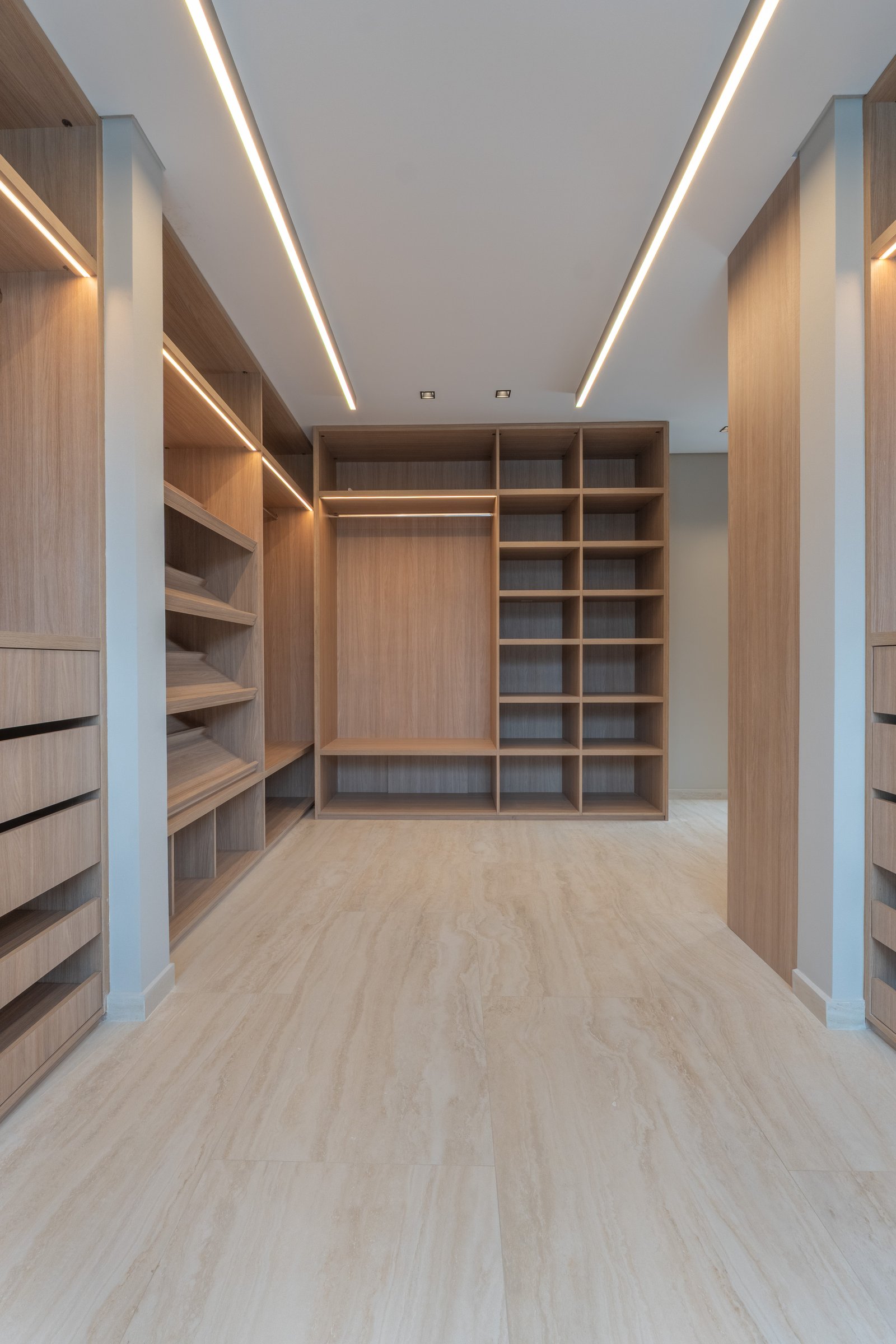 Closet moderno com amplos armários embutidos de madeira e iluminação indireta — projeto Yacht - Estudio CCWay, por ABEJA CONCEPT, em Av. de la Ribera 560
