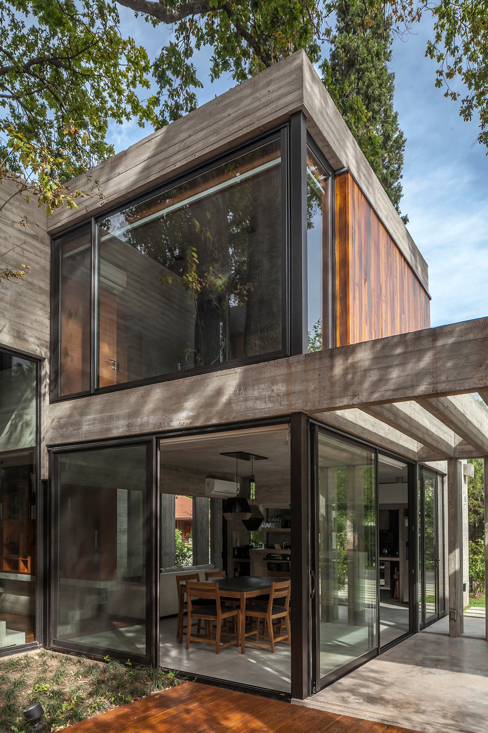 Casa moderna con concreto, madera y grandes ventanales integrados en el bosque — proyecto Casa Aranzazu, por Besonías Almeida arquitectos, en B1667 Tortuguitas