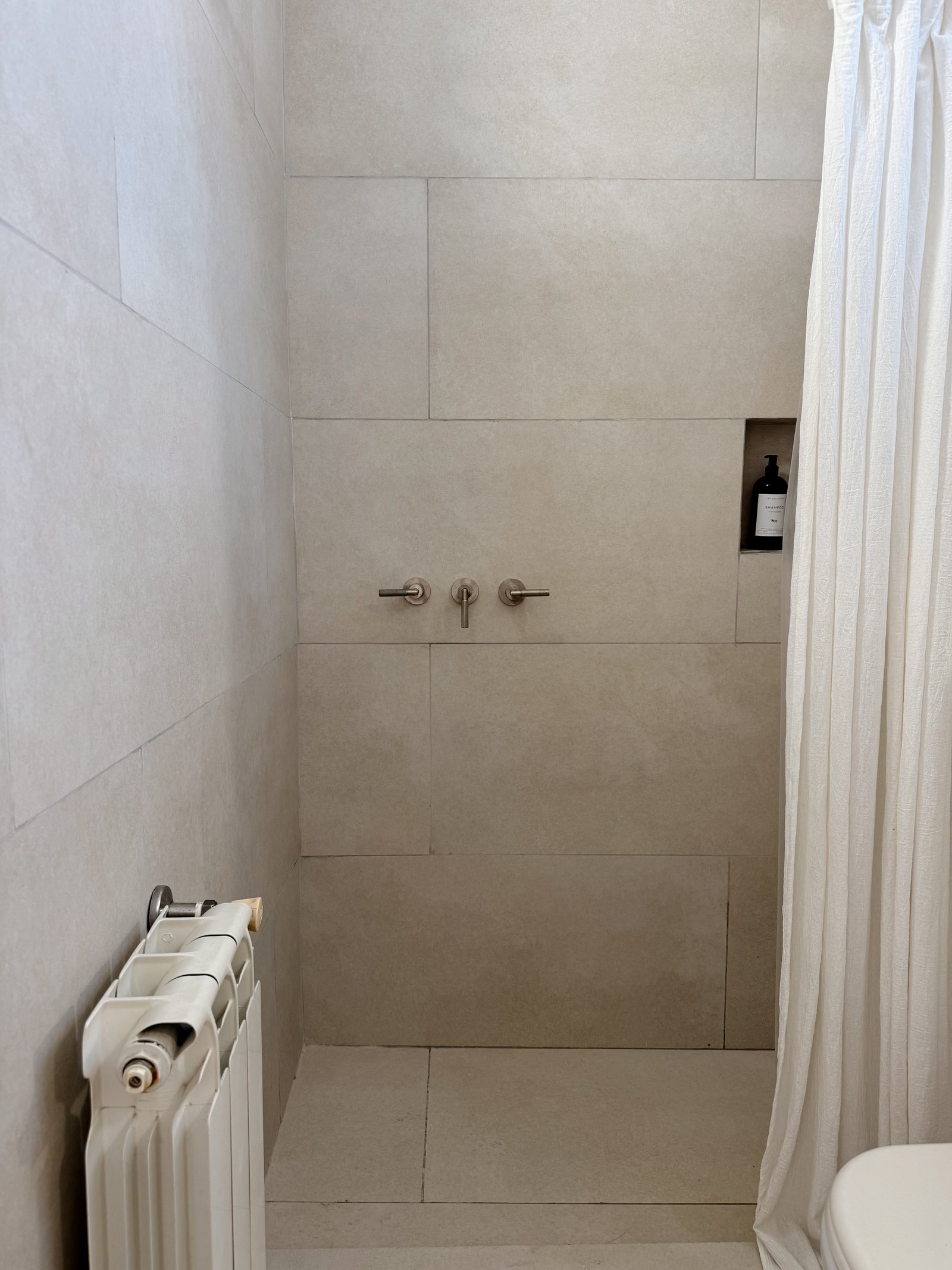 Banheiro minimalista com pedra cinza e radiador branco — projeto Cabrera, por Estudio BDM, em Cdad. Autónoma de Buenos Aires