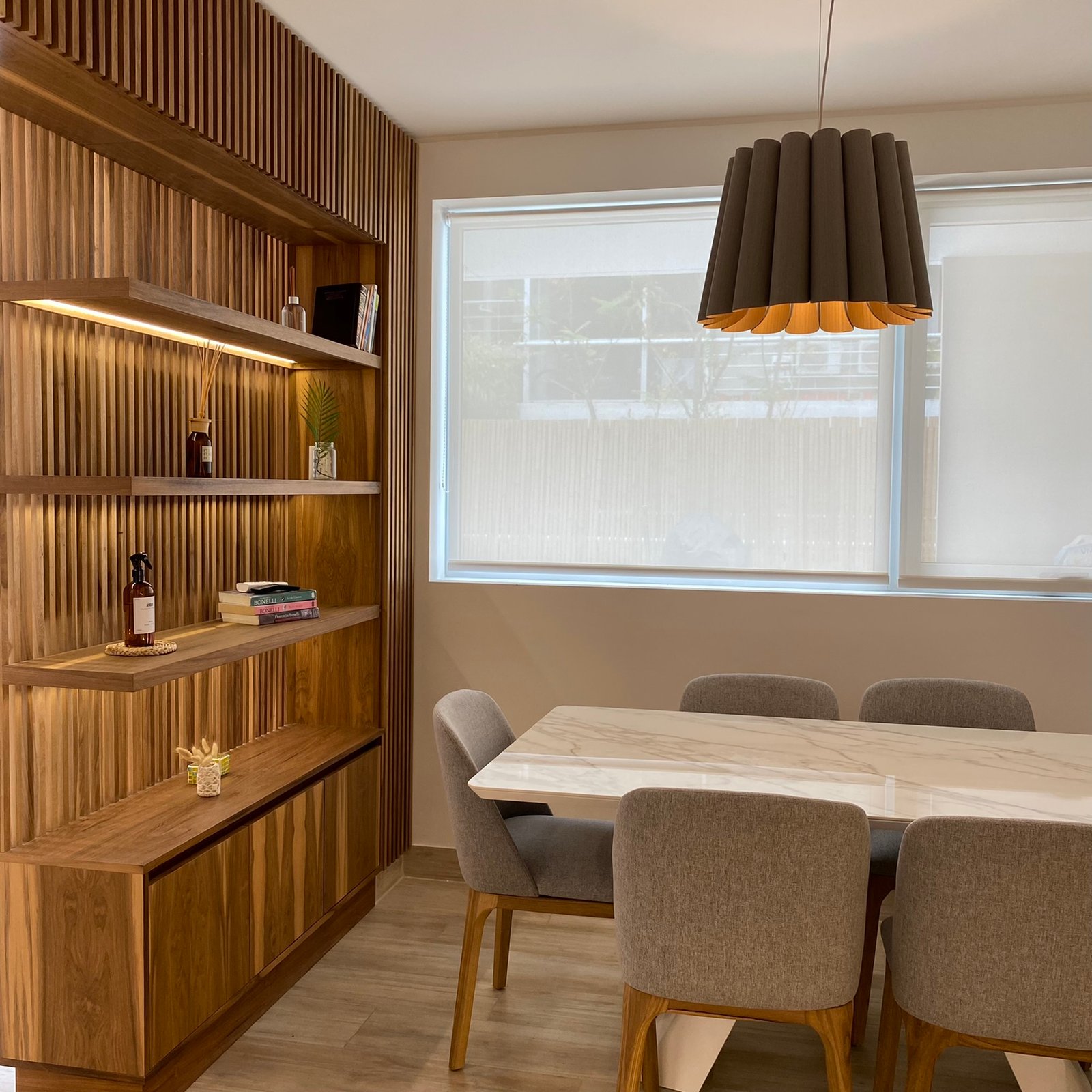 Sala de jantar moderna com parede de ripas de madeira e lustre — projeto Nicolas Repetto, por MDBK Arquitectura, em Caballito