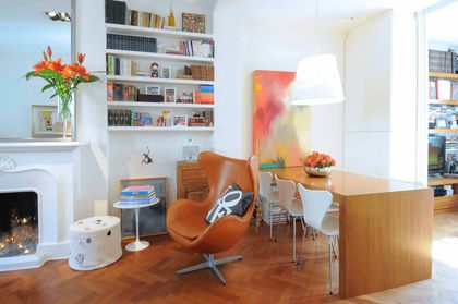 Living contemporáneo con sillón naranja, estantería blanca y piso de madera — proyecto Santa Fe, por Estudio Diez Muzzio, en CABA