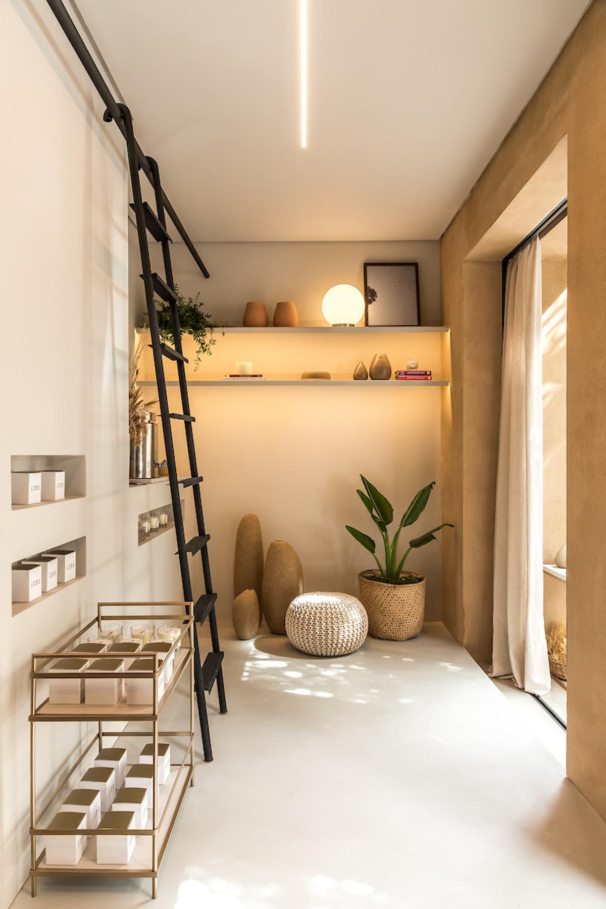 Espaço comercial com prateleiras iluminadas, escada decorativa e objetos de design — projeto Esmo, por Boscardin Corsi Arquitetura