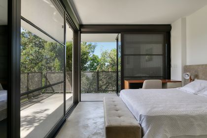 Dormitorio moderno con cama blanca y terraza con vista al jardín — proyecto Casa das Pedras, por Tetro Arquitetura