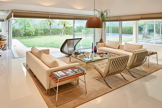 Living contemporaneo con grandes ventanales, sofá beige y sillas de diseño — proyecto Casa Tenn, por Toledo Arquitetura E Design