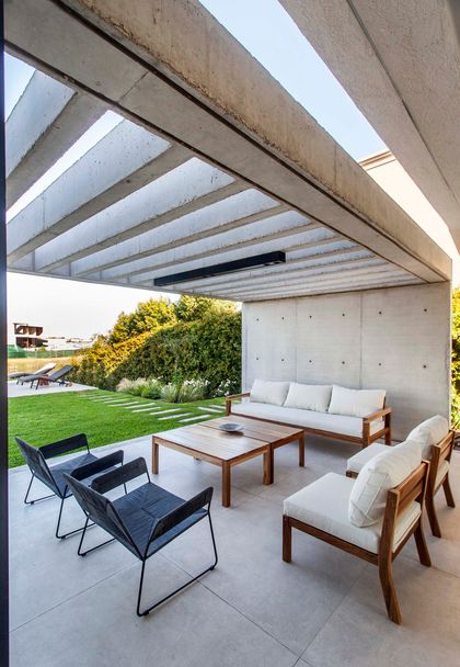 Patio moderno con pérgola de hormigón y muebles blancos — proyecto CASA J2M, por GMARQ, en Belén de Escobar