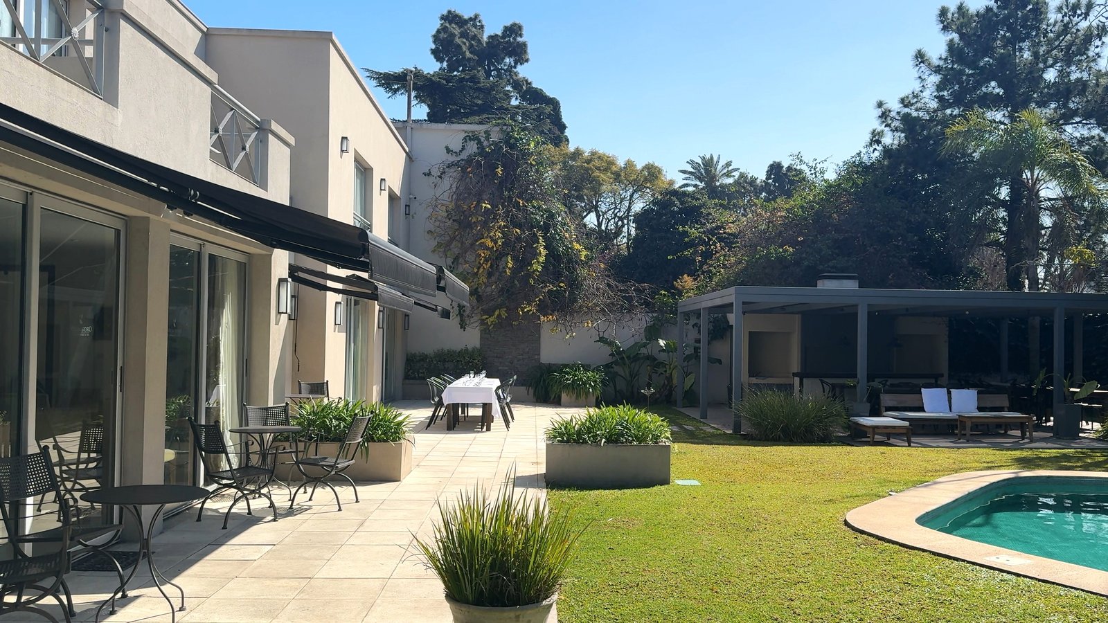 Área externa moderna com piscina, deck e vegetação — projeto Villa Isidro Hotel Boutique & Spa, por Hermann Arquitectos, em San Isidro