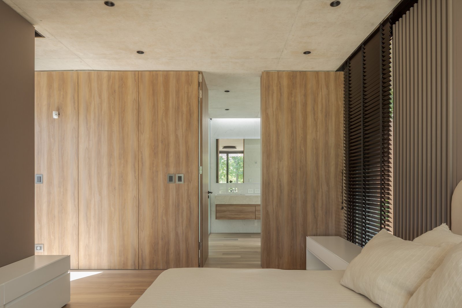 Dormitorio moderno con paredes de madera y techo de hormigón — proyecto Casa PLANALTO, por Grupo CRBN, en Av. Pres. Perón 10298